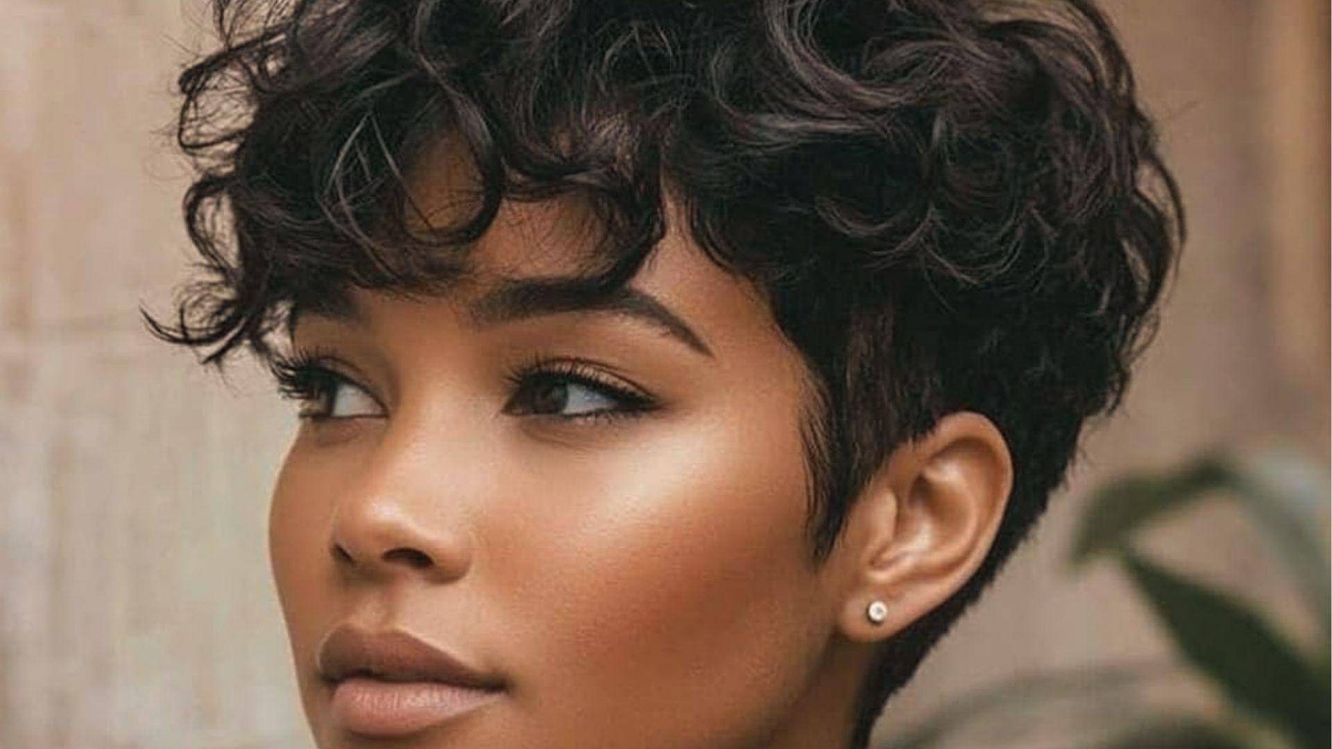 Woman with curly, tapered sides, soft bangs, neutral background, stud earring