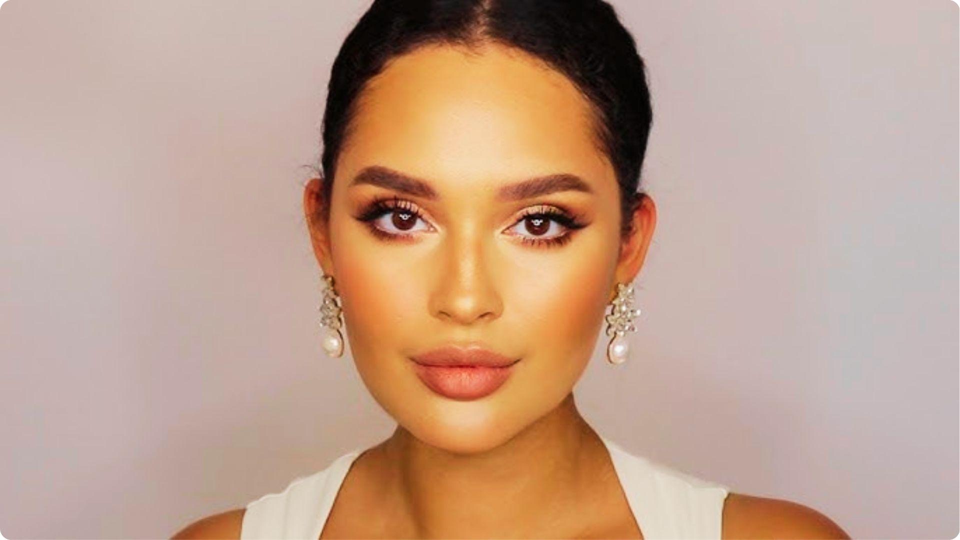 Portrait of a bride with a sleek updo, featuring soft glam wedding makeup with feathered brows, peachy nude lips, and subtle eyeliner.