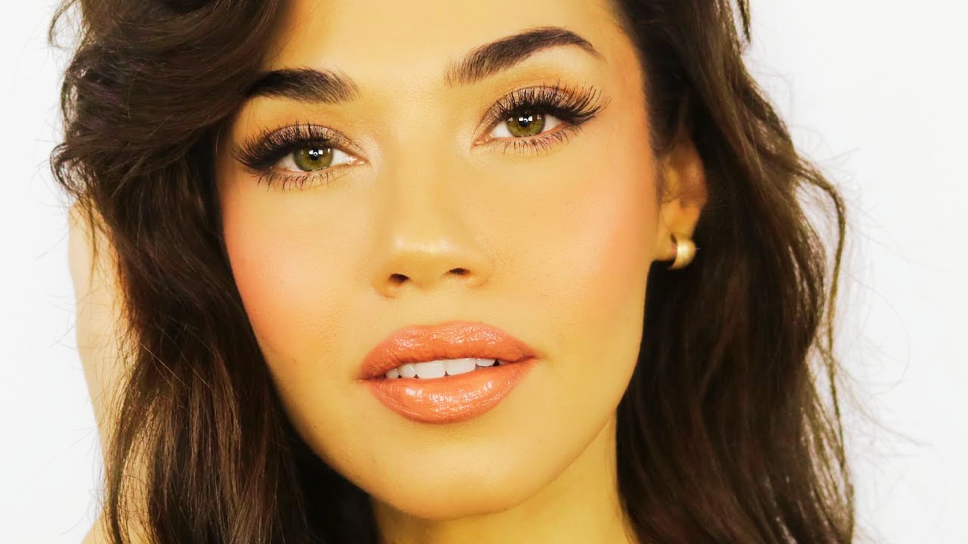 Close-up portrait of a bride with wavy dark hair and radiant dewy skin.