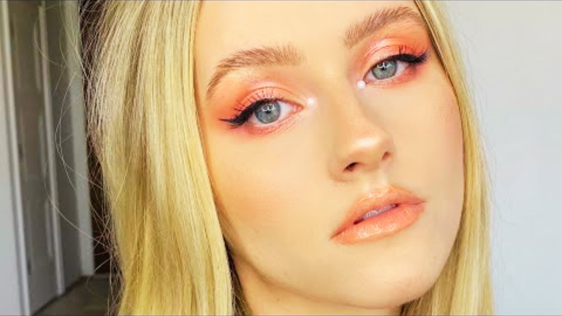 Blonde bride with a subtle pop of coral eyeshadow and pearl accents at the inner corners.