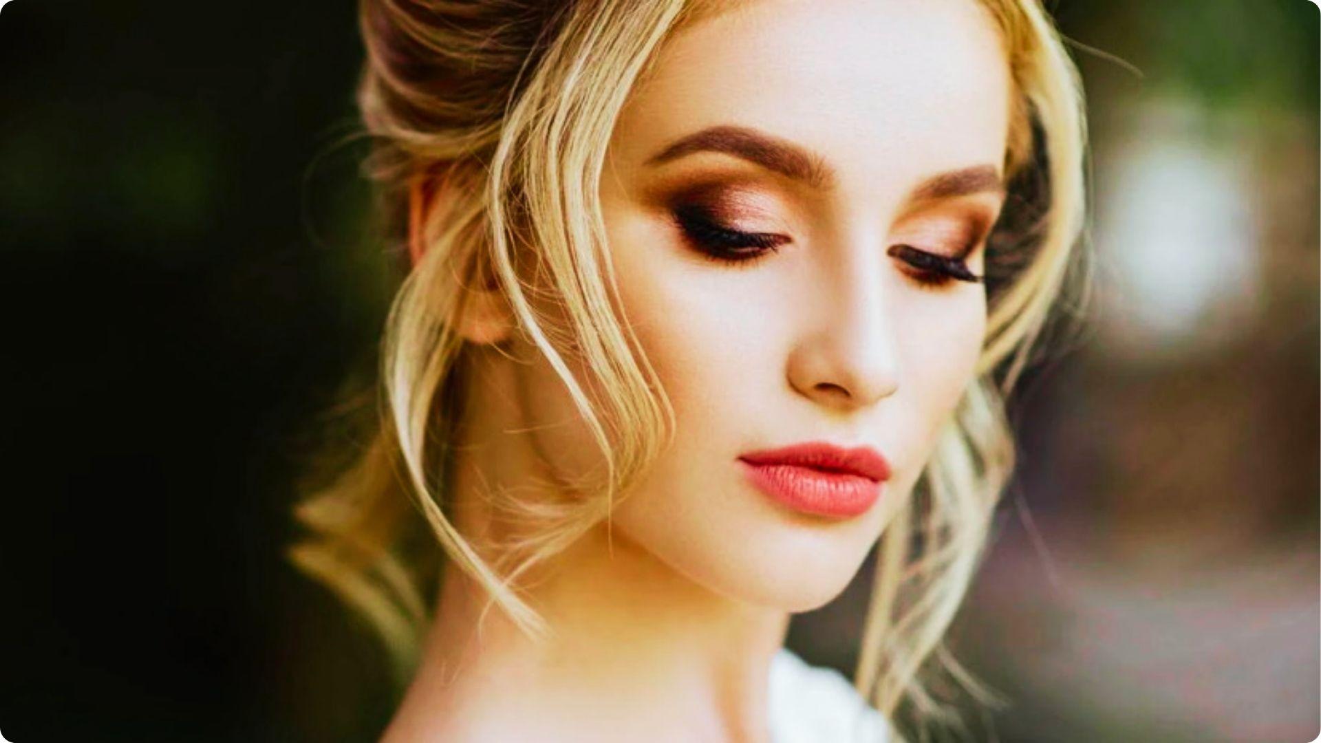 Blonde bride with an updo wearing soft smoky wedding makeup with rose-gold eyeshadow, diffused liner, and satin pink lips.